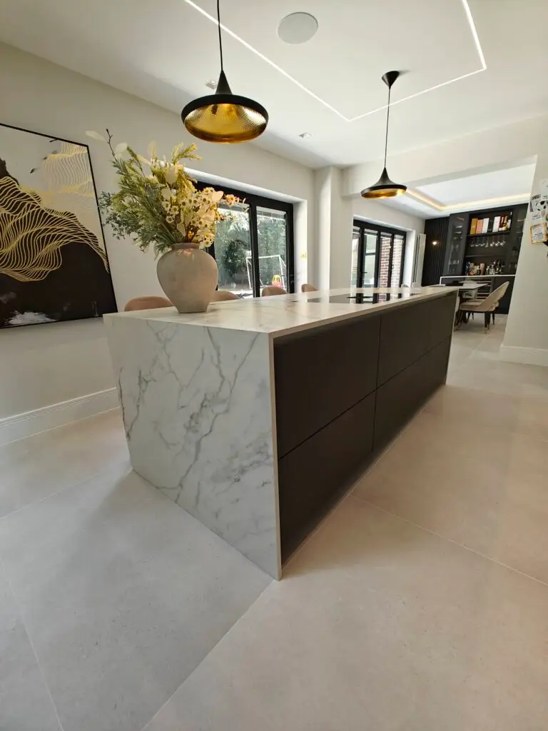 Soft Black PerfectMatt waterfall island with Marazzi Golden White Porcelain worktop in a contemporary Sevenoaks kitchen by Kraus Kitchens